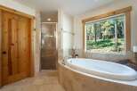 Indulge in relaxation in this luxurious bathroom featuring a spacious soaking tub with a stunning forest view.