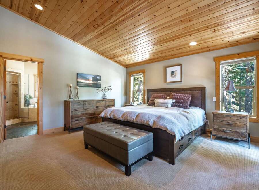 Experience rustic luxury in this master bedroom featuring a spacious king-sized bed with a tufted headboard and plush bedding.