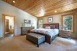 Experience rustic luxury in this master bedroom featuring a spacious king-sized bed with a tufted headboard and plush bedding.