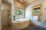 Indulge in relaxation in this luxurious bathroom featuring a spacious corner soaking tub with a scenic forest view.