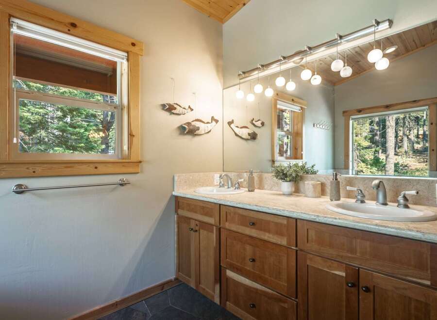 This charming bathroom features a double vanity with ample counter space and natural wood cabinetry.