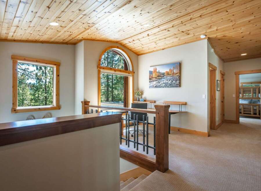 This spacious hallway features a warm and inviting atmosphere with its knotty pine vaulted ceiling and natural wood accents.