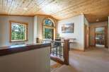This spacious hallway features a warm and inviting atmosphere with its knotty pine vaulted ceiling and natural wood accents.