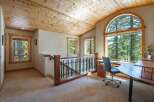 Experience breathtaking forest views from this charming home office, featuring a large arched window that floods the space with natural light.