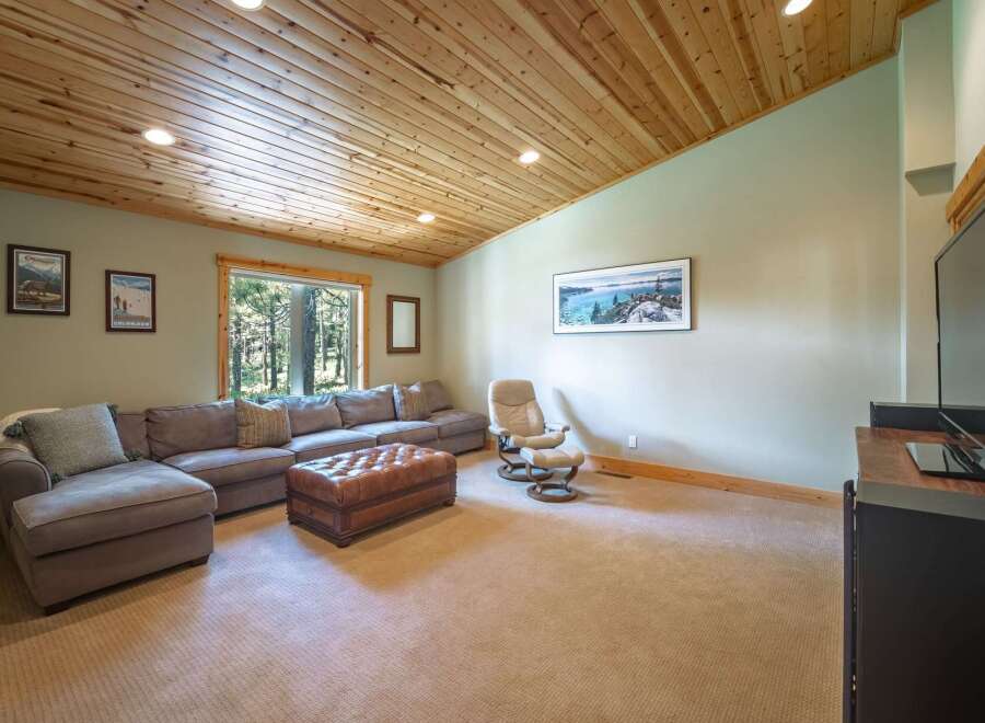 This spacious living room features a large sectional sofa complemented by a plush leather ottoman, perfect for relaxation and entertaining.