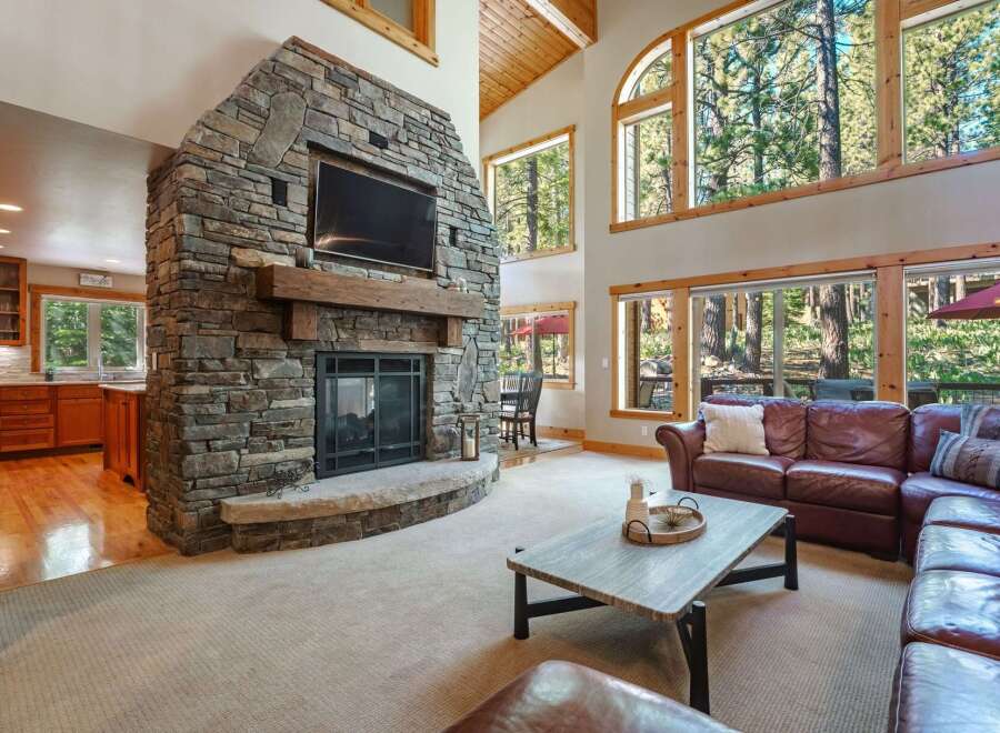 Experience rustic charm and modern comfort in this spacious living area, featuring a grand floor-to-ceiling stone fireplace as the centerpiece.