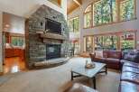 Experience rustic charm and modern comfort in this spacious living area, featuring a grand floor-to-ceiling stone fireplace as the centerpiece.
