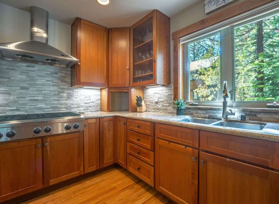 This beautifully appointed kitchen features warm cherry wood cabinetry and a sleek stainless steel range hood.