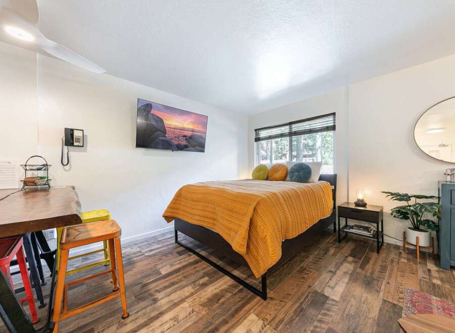 Experience comfort and style in this inviting bedroom, featuring a plush bed adorned with a vibrant orange quilt and decorative pillows.