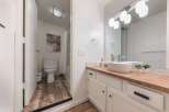 This modern bathroom features a sleek vanity with a vessel sink and a butcher block countertop, complemented by a separate toilet and bathtub area.