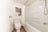 This bathroom features a clean and modern design with a white toilet and bathtub.