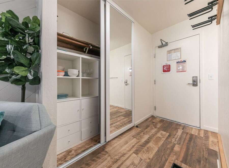 Discover smart storage solutions in this inviting space, featuring a mirrored closet and a built-in shelving unit perfect for organizing kitchenware.
