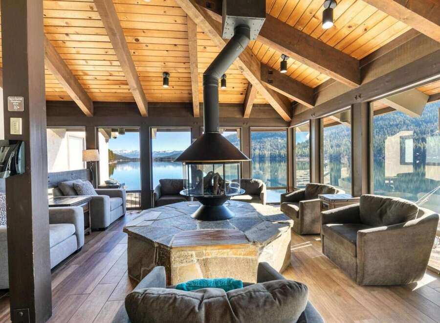 Experience breathtaking lake and mountain views from this stunning living area, featuring a modern fireplace as the centerpiece.