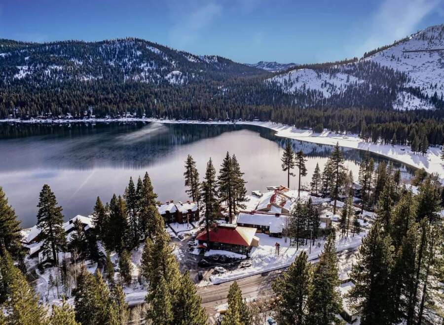Experience the serene beauty of this winter wonderland property, nestled beside a tranquil lake and surrounded by snow-dusted pine forests.