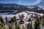 Experience the serene beauty of this winter wonderland property, nestled beside a tranquil lake and surrounded by snow-dusted pine forests.