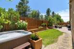 Escape to your private backyard oasis, featuring a luxurious hot tub perfect for relaxation and a beautifully landscaped garden with tiered wooden planters and a built-in bench.
