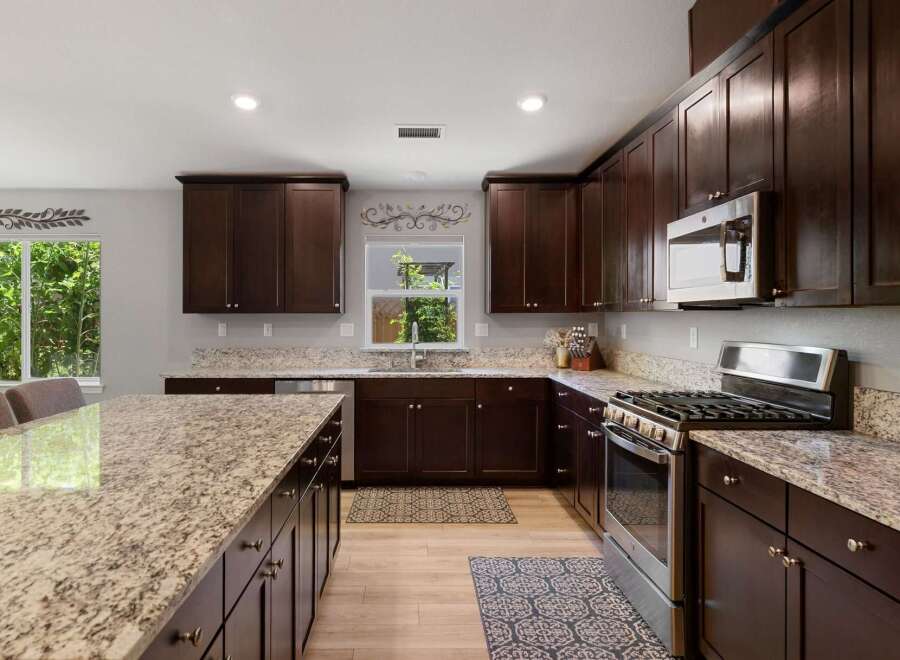 Experience luxury in this stunning kitchen featuring rich, dark wood cabinetry and elegant granite countertops.