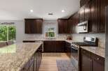 Experience luxury in this stunning kitchen featuring rich, dark wood cabinetry and elegant granite countertops.