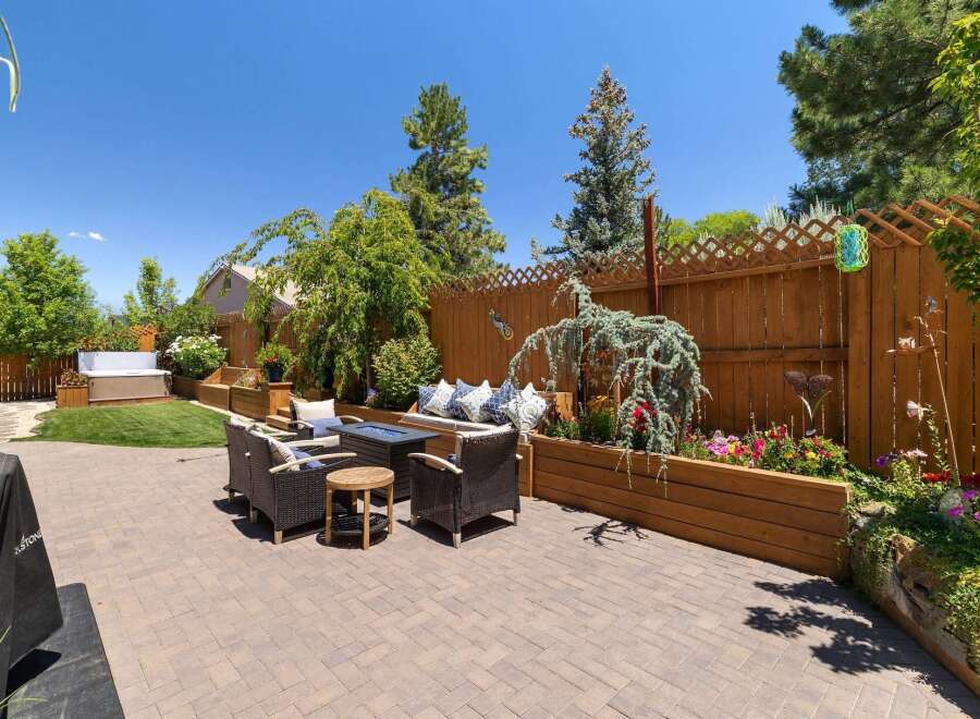 This beautifully landscaped backyard offers a luxurious outdoor living experience with a spacious patio, comfortable seating area, and a built-in hot tub.