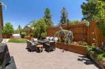 This beautifully landscaped backyard offers a luxurious outdoor living experience with a spacious patio, comfortable seating area, and a built-in hot tub.
