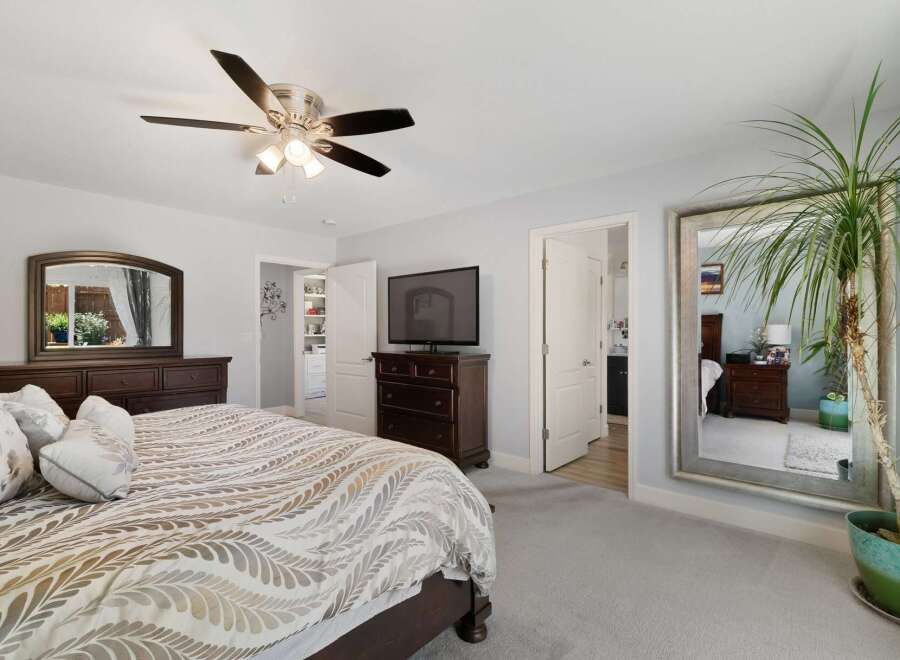 Experience ultimate comfort in this spacious master bedroom, featuring a plush king-size bed with a decorative duvet and a convenient ceiling fan for year-round comfort.