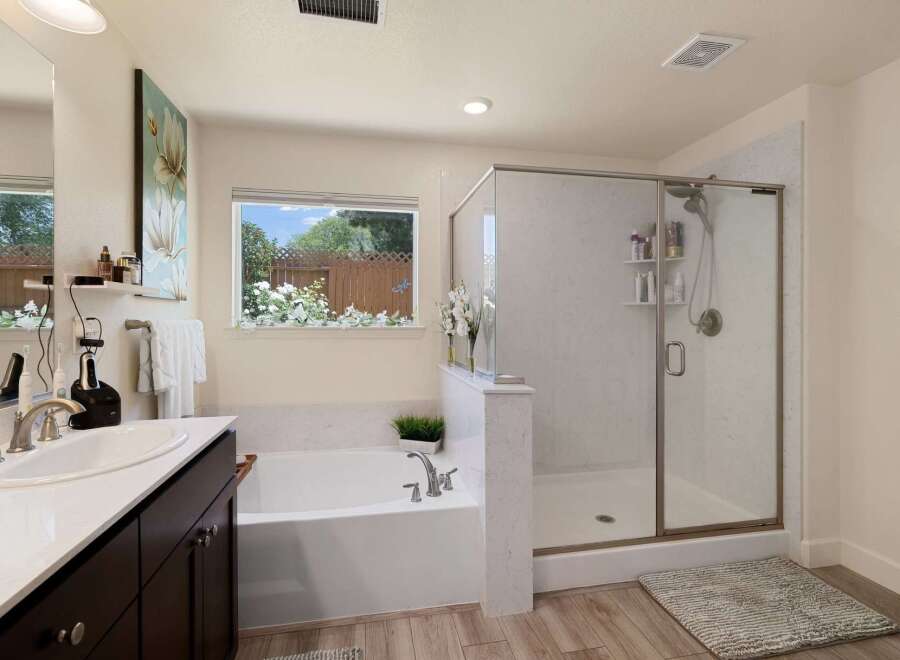 Experience luxury in this stunning bathroom featuring a spacious soaking tub and a separate glass-enclosed shower with marble-look tile.