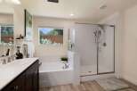 Experience luxury in this stunning bathroom featuring a spacious soaking tub and a separate glass-enclosed shower with marble-look tile.