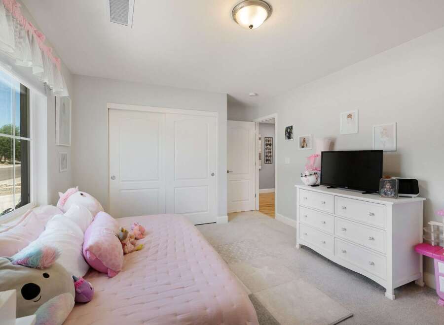 This charming bedroom features a cozy bed adorned with plush pillows and a soft pink quilt, perfect for relaxation.