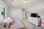 This charming bedroom features a cozy bed adorned with plush pillows and a soft pink quilt, perfect for relaxation.