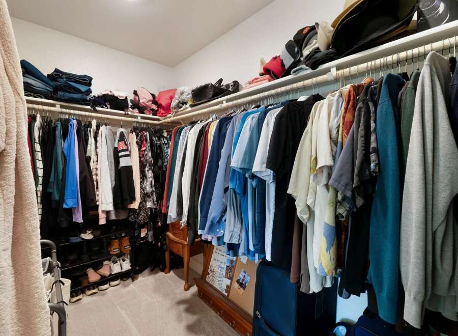 Discover ample storage in this spacious walk-in closet, featuring organized shelving and multiple hanging racks perfect for any wardrobe.