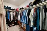 Discover ample storage in this spacious walk-in closet, featuring organized shelving and multiple hanging racks perfect for any wardrobe.