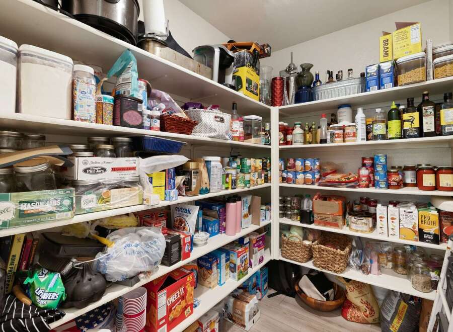 This spacious pantry offers ample storage for all your culinary needs, featuring well-organized shelves stocked with a variety of canned goods, dry ingredients, and kitchen essentials.