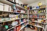 This spacious pantry offers ample storage for all your culinary needs, featuring well-organized shelves stocked with a variety of canned goods, dry ingredients, and kitchen essentials.