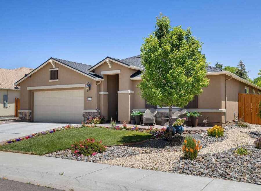 Discover this charming single-story home featuring a welcoming facade with a well-maintained lawn and vibrant flower beds.