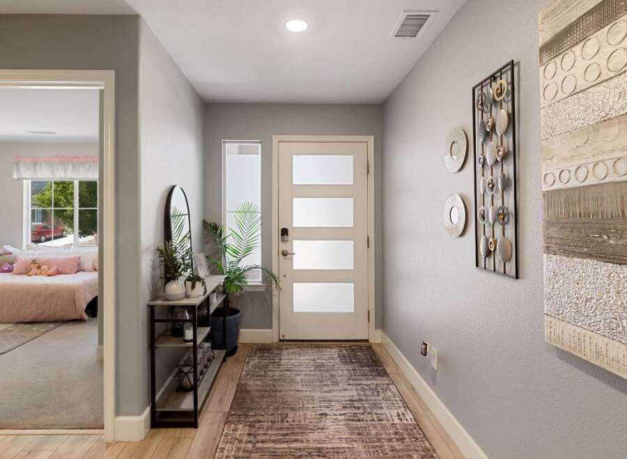 Step into this welcoming entryway featuring a modern door with frosted glass panels, leading into a bright and airy hallway.