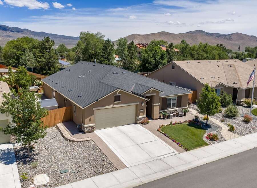 Discover this charming single-family home featuring a spacious two-car garage and a well-maintained front yard with lush green grass and colorful flower beds.