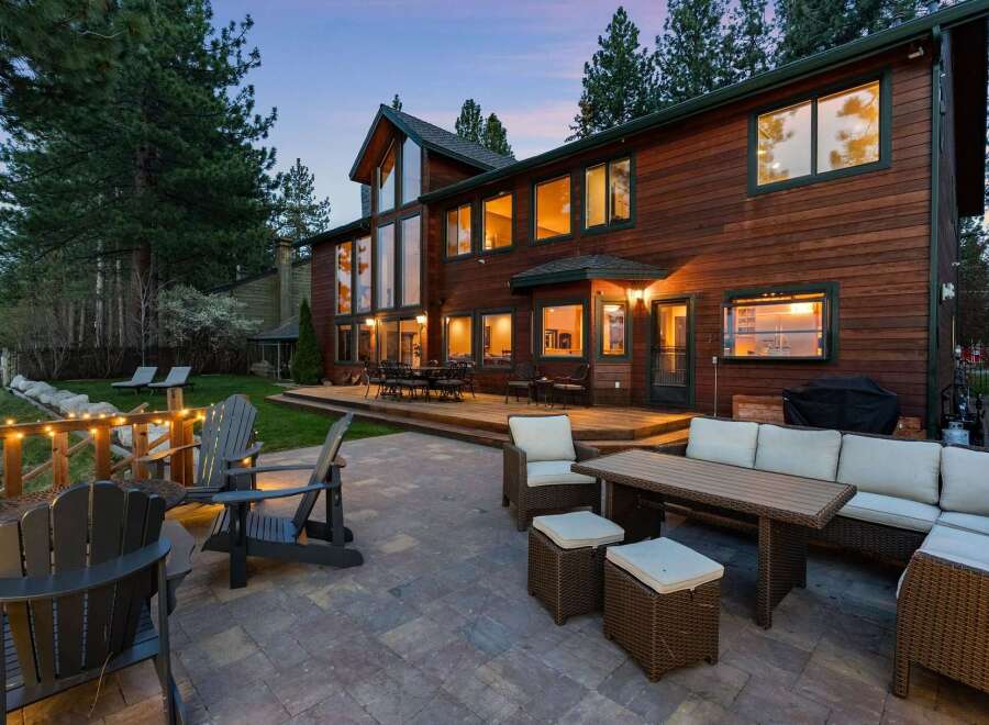 Experience luxurious outdoor living with this stunning property featuring a spacious wooden deck and a stone patio perfect for entertaining.