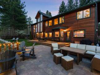 Experience luxurious outdoor living with this stunning property featuring a spacious wooden deck and a stone patio perfect for entertaining.
