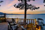 Experience breathtaking sunset views from this stunning lakefront property's expansive deck, complete with cozy Adirondack chairs and charming string lights.