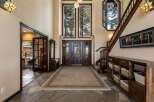 Step into a grand foyer featuring a stunning double-door entrance with intricate glass inlays, leading to a spacious living area.