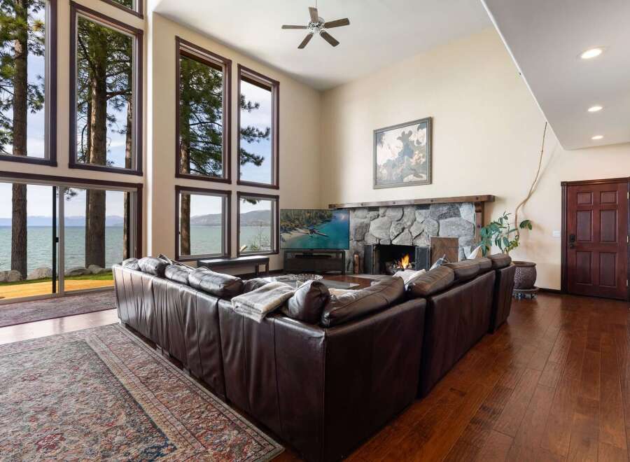 Experience breathtaking lake views from this stunning living room, featuring a massive stone fireplace and expansive windows that bring the outdoors in.