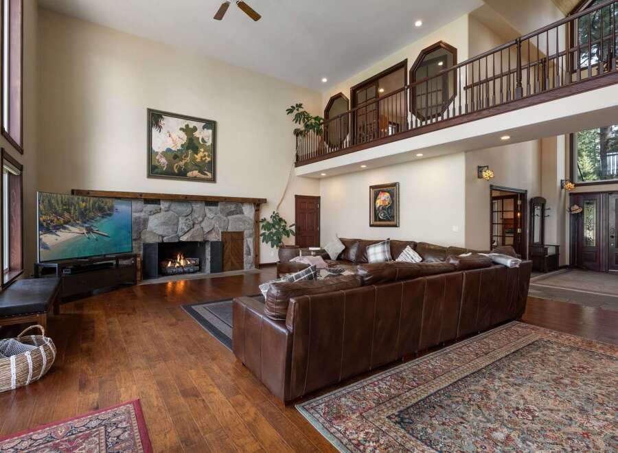 Experience luxury living in this grand living room, featuring a soaring stone fireplace and a stunning two-story balcony overlooking the space.