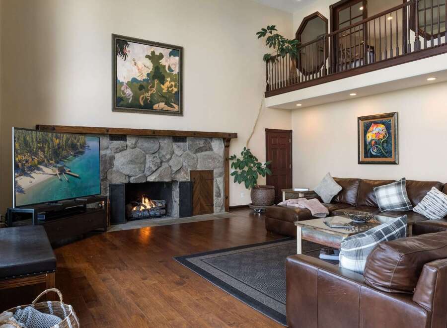 Experience luxury living in this stunning great room, featuring a grand stone fireplace and a soaring ceiling with a lofted balcony.