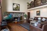 Experience luxury living in this stunning great room, featuring a grand stone fireplace and a soaring ceiling with a lofted balcony.