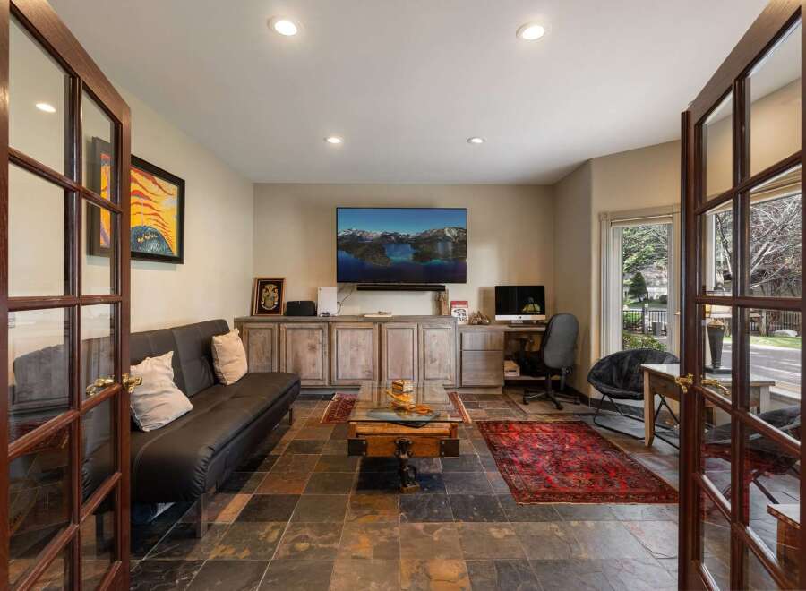 This versatile room offers a comfortable living area with a sleek black sofa and a large flat-screen TV, perfect for entertainment.