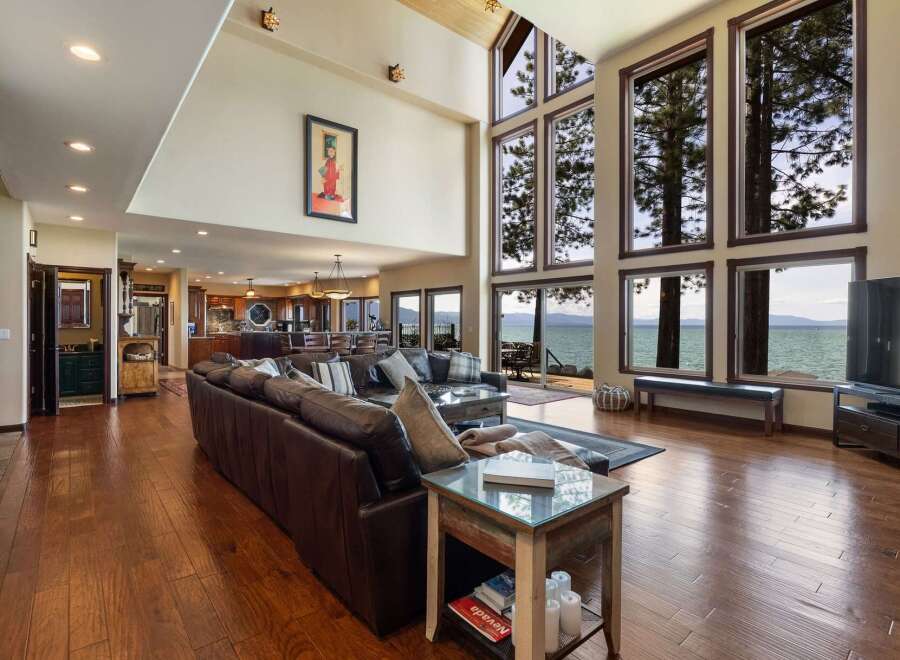 Experience breathtaking lake views from this stunning living room, featuring a spacious sectional sofa and a wall of expansive windows.
