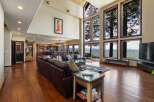 Experience breathtaking lake views from this stunning living room, featuring a spacious sectional sofa and a wall of expansive windows.