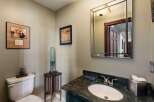 This powder room offers a sophisticated ambiance with its elegant vanity featuring a dark green cabinet and a striking marble countertop.