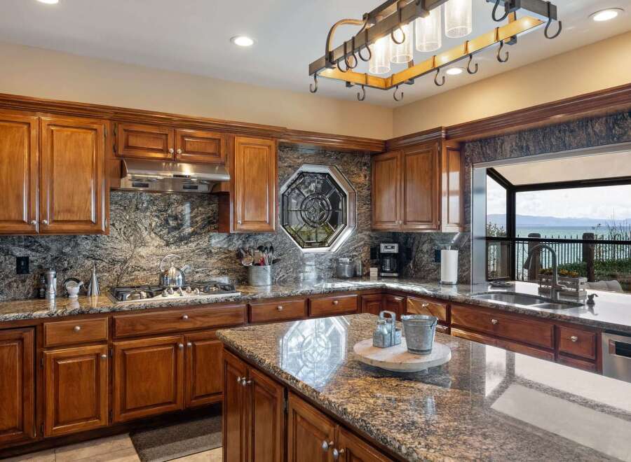 Experience breathtaking ocean views from this stunning kitchen, featuring rich wood cabinetry and elegant granite countertops.