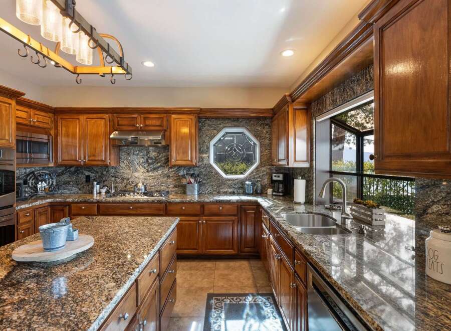 Experience luxury in this stunning kitchen featuring rich wood cabinetry and exquisite granite countertops.